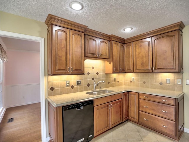 kitchen featuring brown cabinets, dishwasher, and a sink