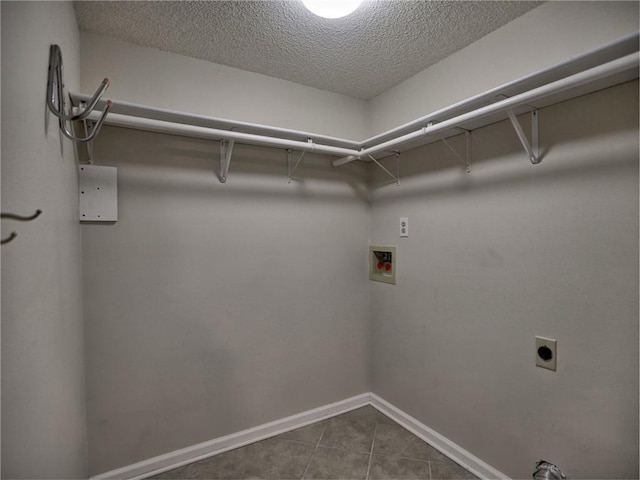 clothes washing area featuring dark tile patterned floors, baseboards, hookup for an electric dryer, hookup for a washing machine, and laundry area