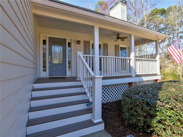 entrance to property with covered porch, a chimney, and ceiling fan