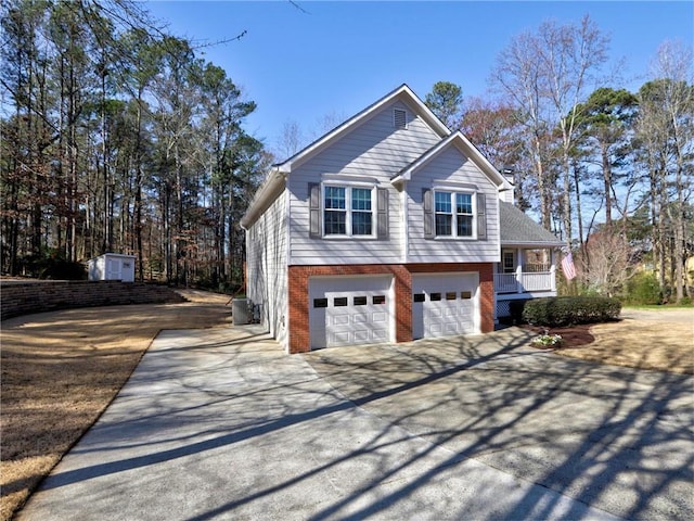 view of side of home with a garage, brick siding, covered porch, and concrete driveway