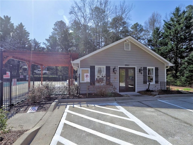 view of front of property featuring french doors, a pergola, and fence