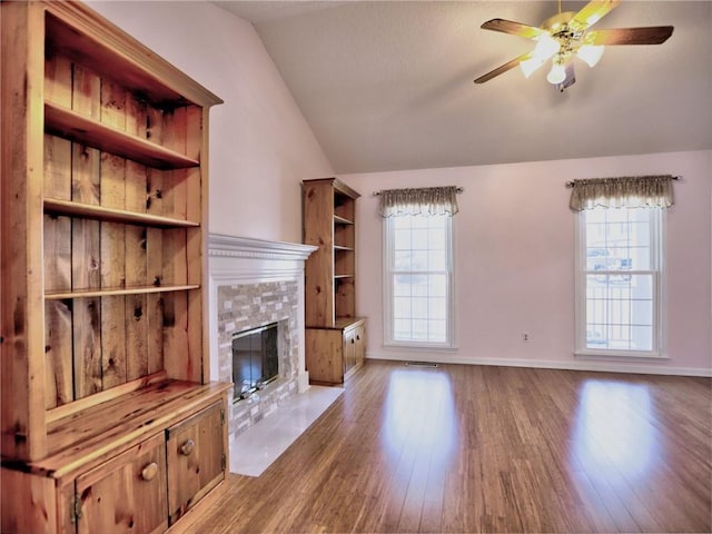 unfurnished living room featuring vaulted ceiling, wood finished floors, and a healthy amount of sunlight