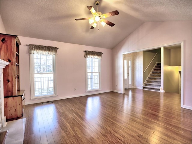 unfurnished living room featuring a ceiling fan, a textured ceiling, wood finished floors, stairway, and lofted ceiling