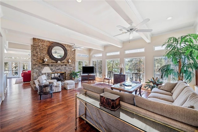 living room featuring a ceiling fan, dark wood-style floors, ornamental molding, a fireplace, and beam ceiling