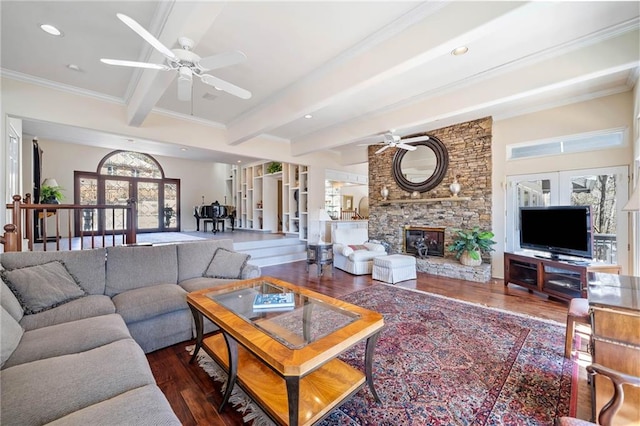 living room with french doors, beam ceiling, ceiling fan, a stone fireplace, and wood finished floors