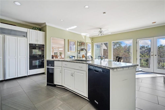 kitchen featuring crown molding, a center island with sink, white cabinets, a sink, and black appliances