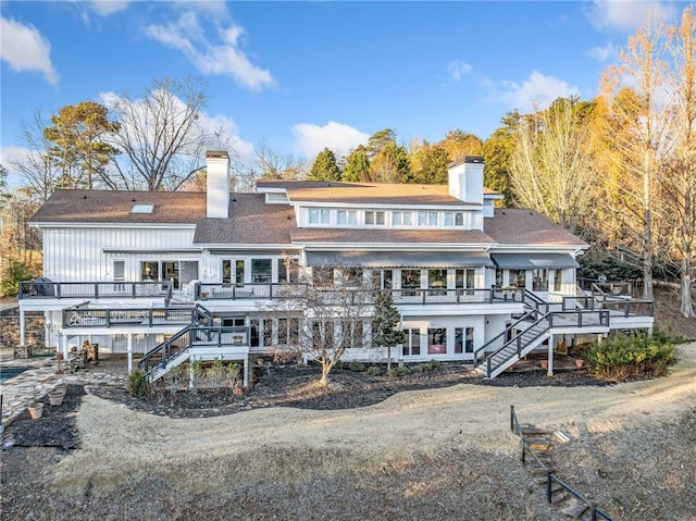 rear view of property featuring a deck, a chimney, and stairway