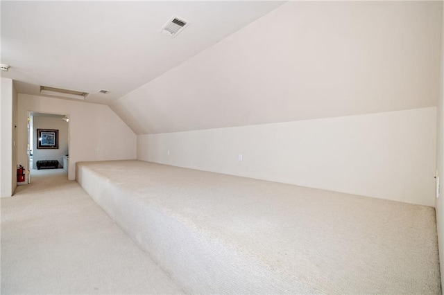 bonus room featuring vaulted ceiling, light carpet, visible vents, and attic access