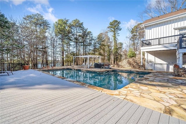 pool with a patio, a wooden deck, and a pergola