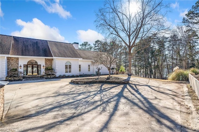 exterior space featuring stone siding, fence, a chimney, and french doors