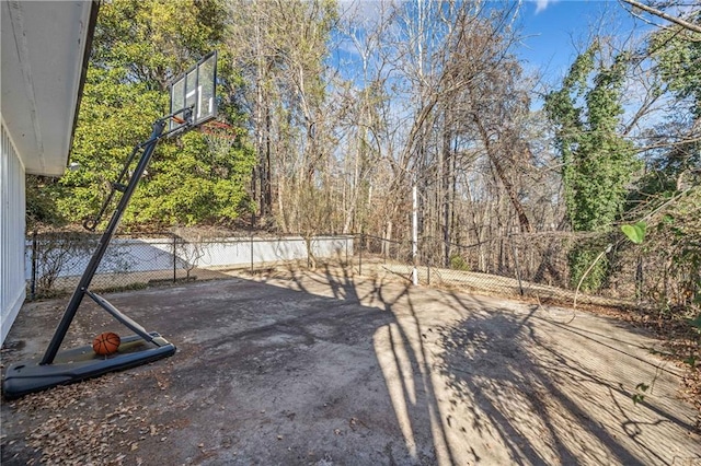 view of yard featuring basketball hoop and fence