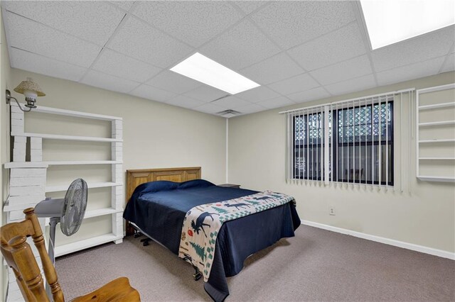 carpeted bedroom featuring a drop ceiling