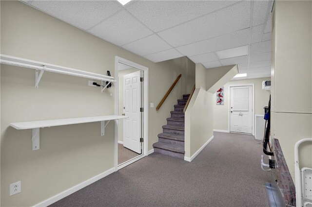 interior space featuring dark colored carpet and a paneled ceiling