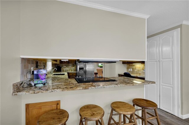 kitchen featuring dark hardwood / wood-style flooring, sink, tasteful backsplash, ornamental molding, and stainless steel fridge