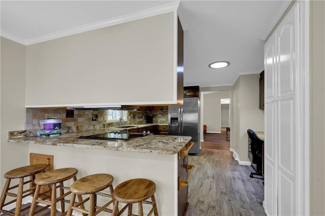 kitchen with kitchen peninsula, light hardwood / wood-style flooring, stainless steel fridge with ice dispenser, and light stone countertops