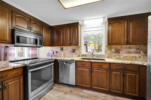 kitchen featuring appliances with stainless steel finishes, sink, light stone counters, and plenty of natural light