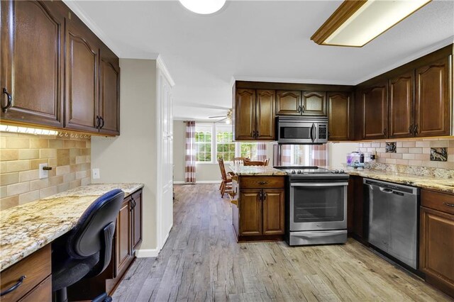 kitchen featuring light stone counters, stainless steel appliances, decorative backsplash, light hardwood / wood-style floors, and ceiling fan