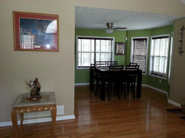 dining space featuring a healthy amount of sunlight, ceiling fan, wood finished floors, and baseboards