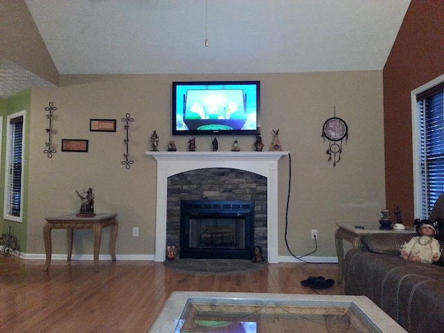 living room with a stone fireplace, wood finished floors, and baseboards