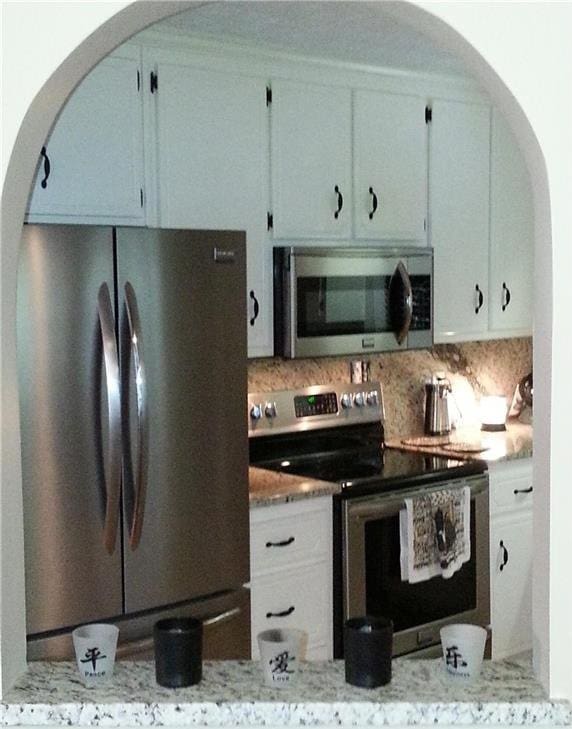 kitchen with tasteful backsplash, stainless steel appliances, and arched walkways
