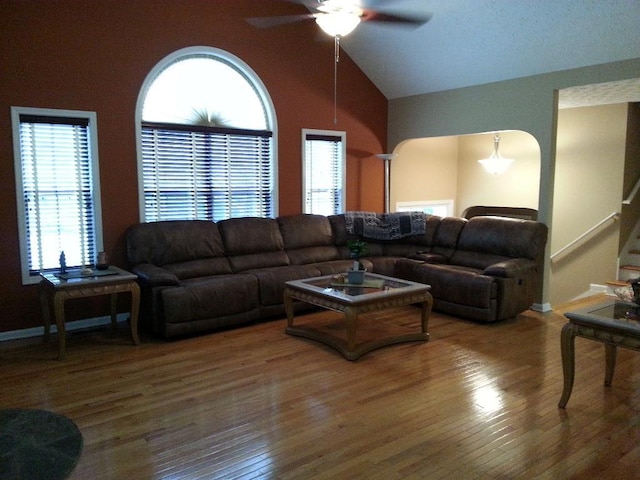living area with lofted ceiling, wood finished floors, ceiling fan, and stairs