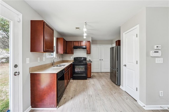 kitchen featuring a sink, visible vents, light wood-style floors, light countertops, and black appliances