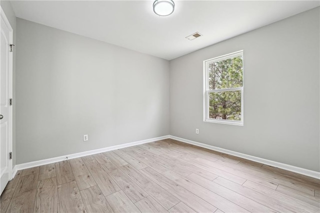 unfurnished room with light wood-type flooring, visible vents, and baseboards