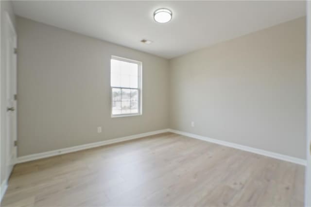 unfurnished room with light wood-type flooring and baseboards