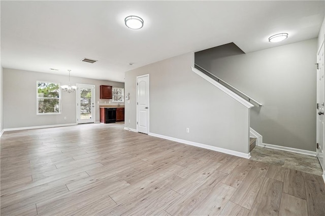 unfurnished living room with light wood-style floors, visible vents, baseboards, and stairs