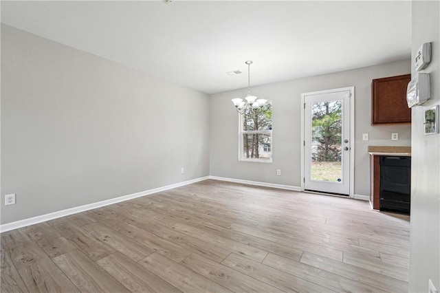 unfurnished dining area featuring light wood-style floors, visible vents, baseboards, and a notable chandelier