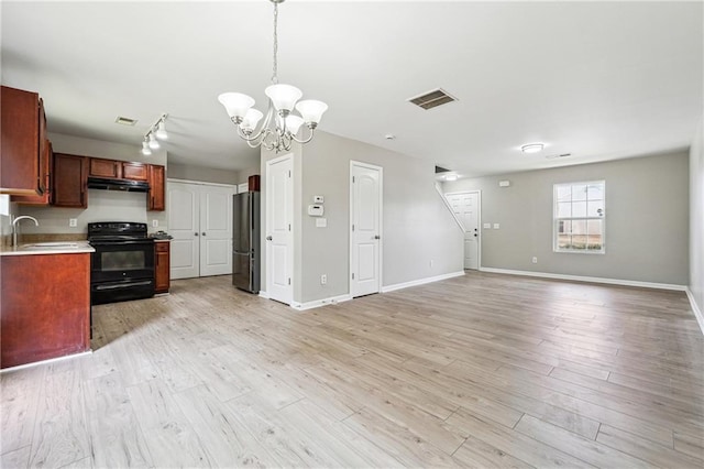 kitchen featuring light countertops, black electric range oven, light wood-style flooring, freestanding refrigerator, and a sink