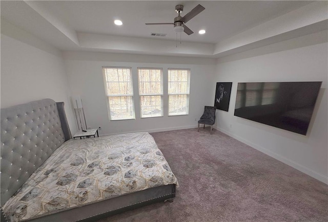 carpeted bedroom with ceiling fan and a raised ceiling