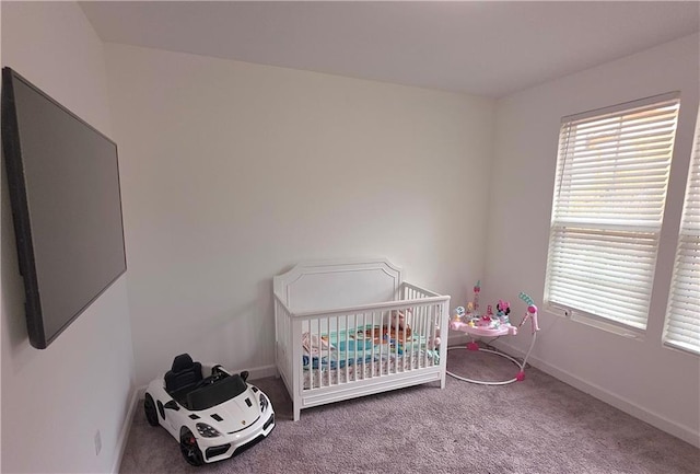 carpeted bedroom featuring multiple windows and a crib