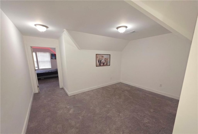 additional living space featuring vaulted ceiling and dark colored carpet