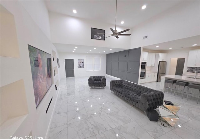 living room with ceiling fan, sink, and a high ceiling