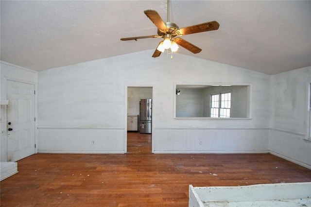 spare room featuring ceiling fan, lofted ceiling, wood finished floors, and a textured ceiling