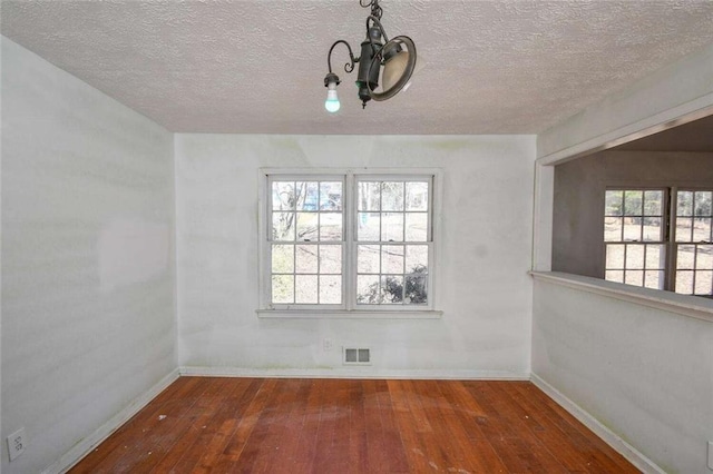 unfurnished dining area with visible vents, baseboards, and hardwood / wood-style flooring