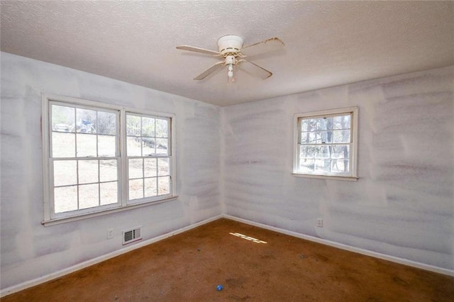 spare room with baseboards, visible vents, a textured ceiling, and ceiling fan