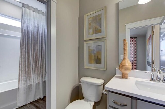 full bathroom with vanity, toilet, shower / bath combo with shower curtain, and wood-type flooring