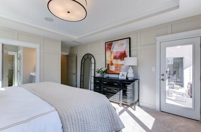 bedroom featuring ensuite bathroom, a raised ceiling, and light colored carpet