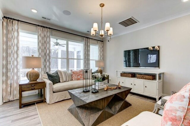 living room with a notable chandelier, light wood-type flooring, and crown molding