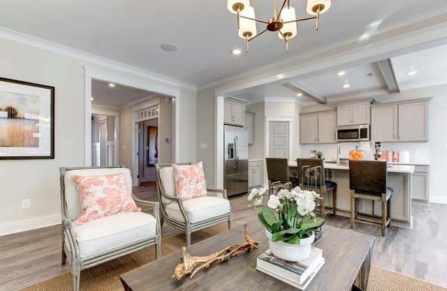 living room with beamed ceiling, ornamental molding, dark wood-type flooring, and a chandelier