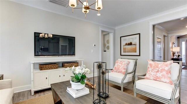 living room featuring wood-type flooring, a notable chandelier, and ornamental molding