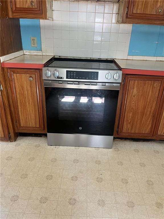 818 Arch Tanner Rd, Bethlehem, GA 30680 - kitchen with stainless steel range with electric cooktop, brown cabinetry, and backsplash