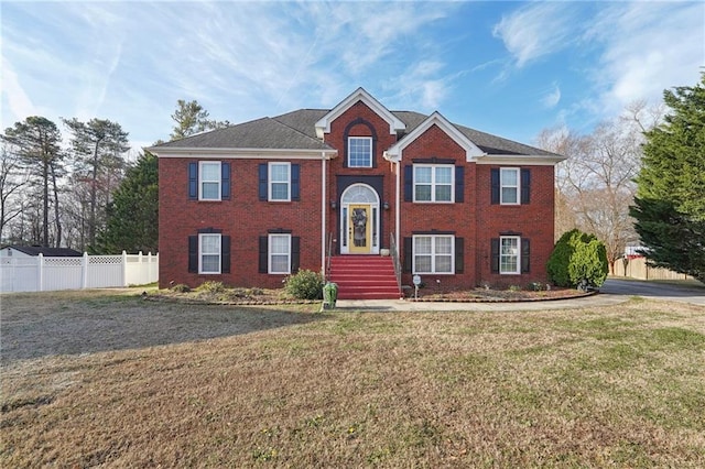 bi-level home featuring brick siding, a front yard, and fence