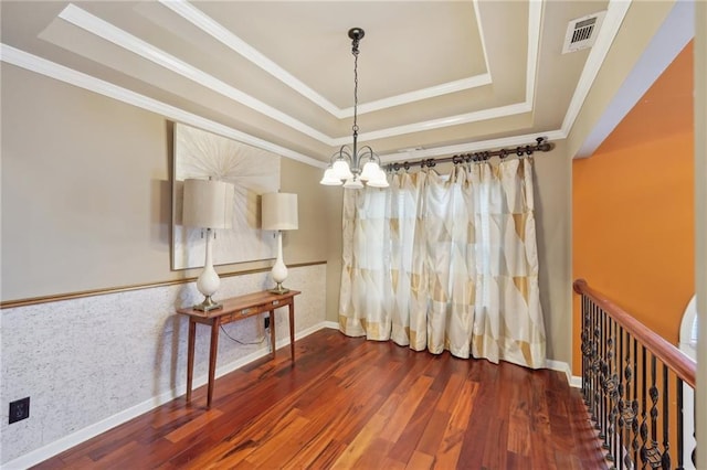 dining space with a raised ceiling, visible vents, a notable chandelier, and wood finished floors