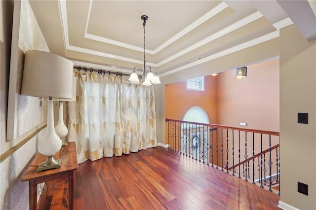 unfurnished room with a tray ceiling, crown molding, visible vents, wood finished floors, and a chandelier