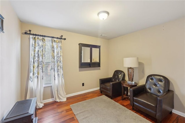 sitting room featuring dark wood-style flooring, visible vents, and baseboards