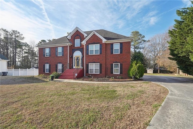 split foyer home featuring brick siding, a front lawn, and fence