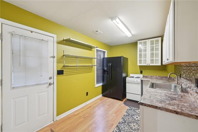 kitchen with white electric stove, a sink, white cabinetry, black refrigerator with ice dispenser, and glass insert cabinets